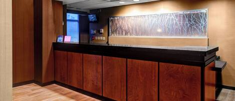 A reception desk with a wooden finish, a modern light fixture, and a decorative wall panel.