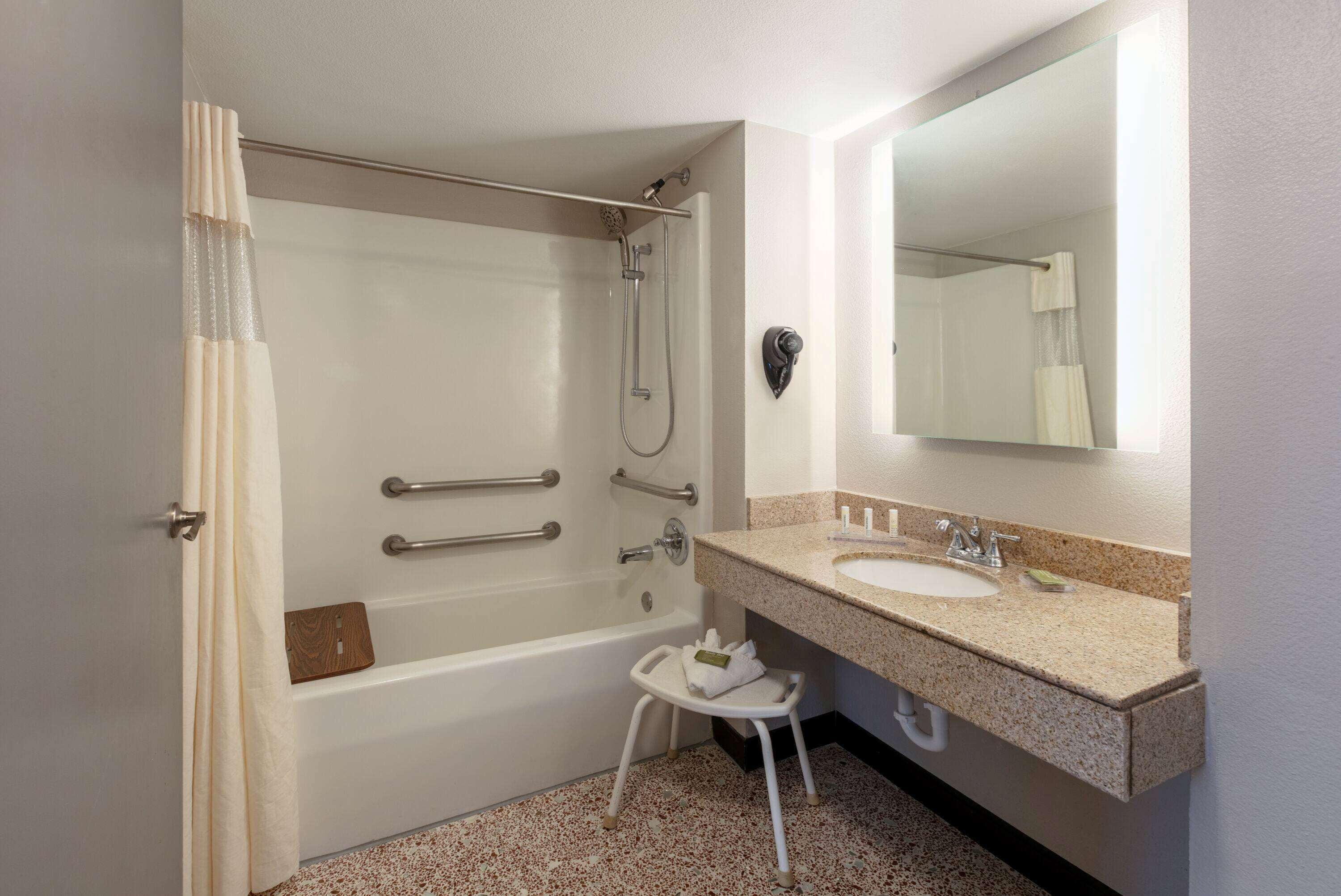 A bathroom with a bathtub, a shower, a sink, and a mirror.