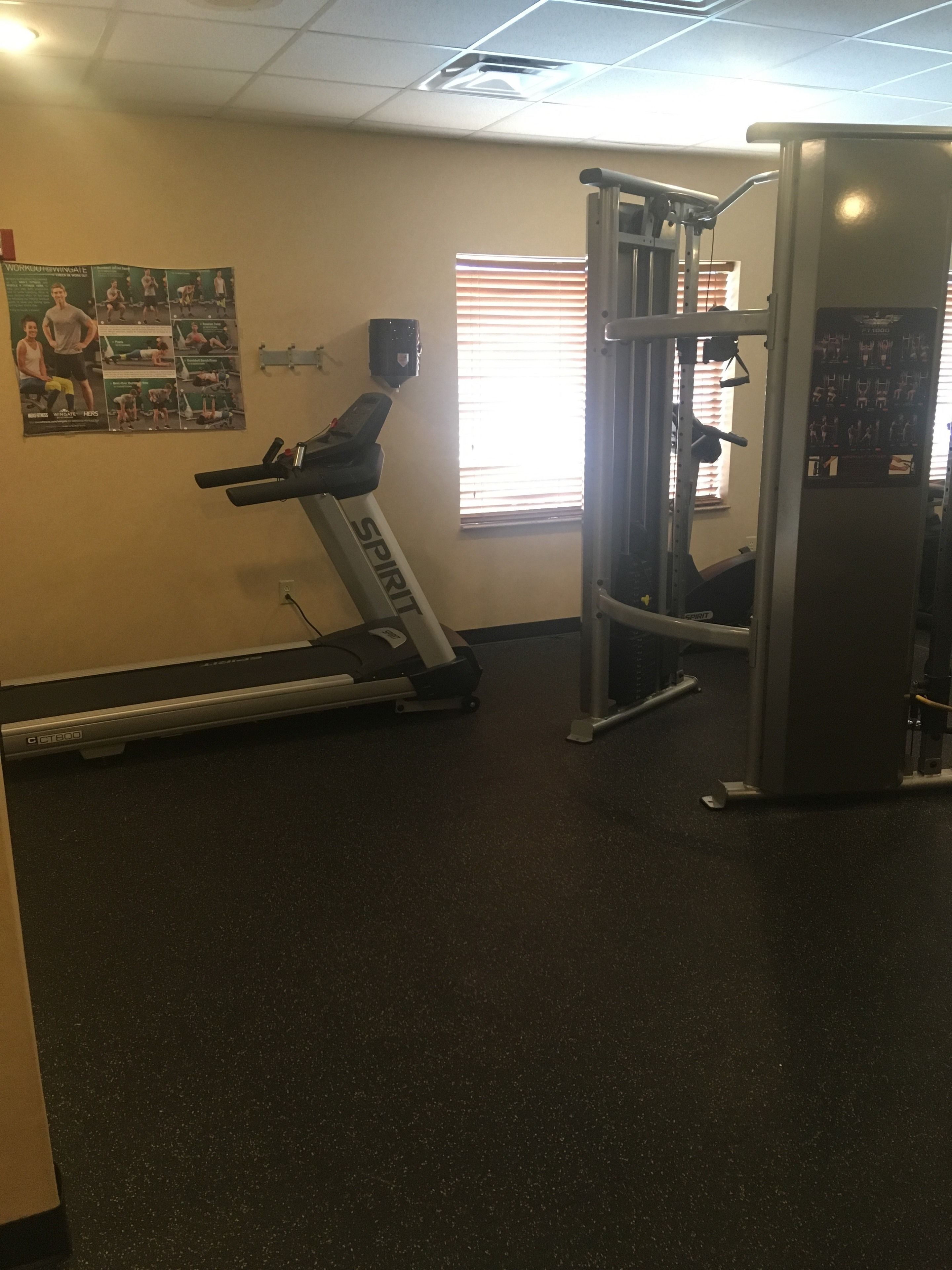 A gym with a treadmill, a pull-up bar, and a wall poster.