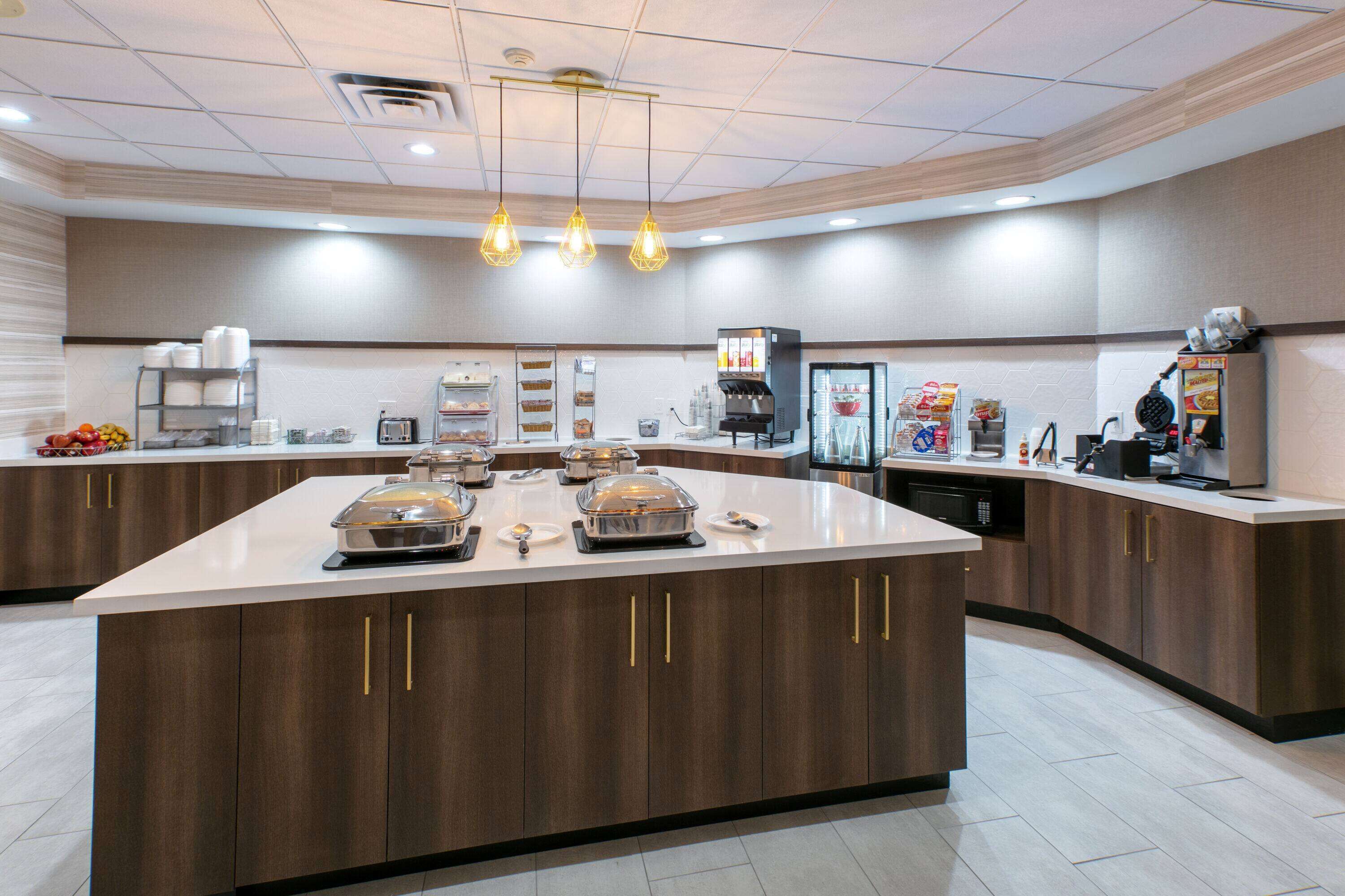 A modern kitchen with a large island, equipped with various appliances and food items.
