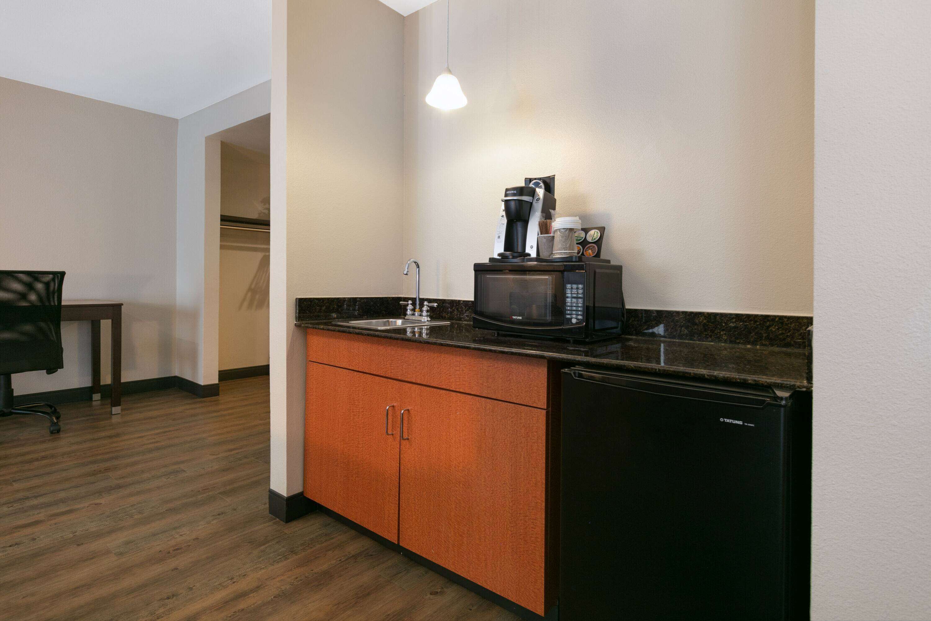 A compact kitchen with a microwave, coffee maker, and refrigerator.