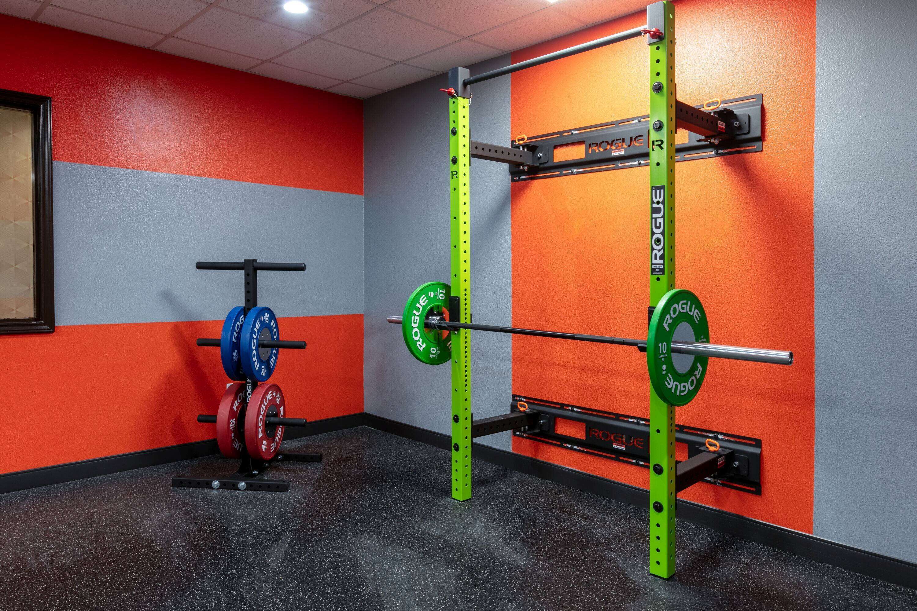 A gym with weightlifting equipment, including a squat rack and barbell.