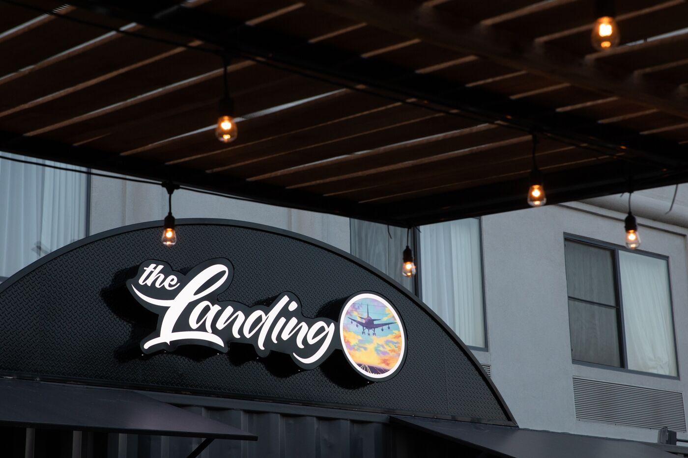 Un letrero con el texto 'the Landing' y un logotipo circular con un avión.