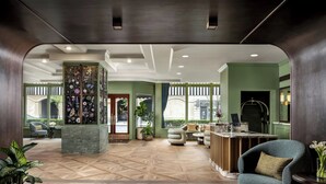 A spacious lobby with a herringbone-patterned floor, a reception desk, seating area, and large windows. - The Louie, A Davenport Hotel, Autograph Collection® (Spokane)
