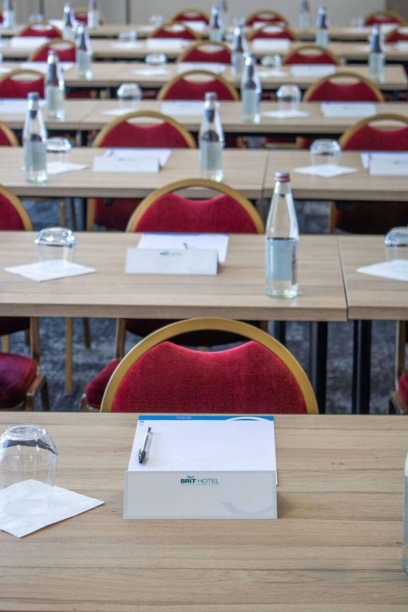 A conference room with multiple tables, each equipped with a water bottle, a glass, and a name tag holder.