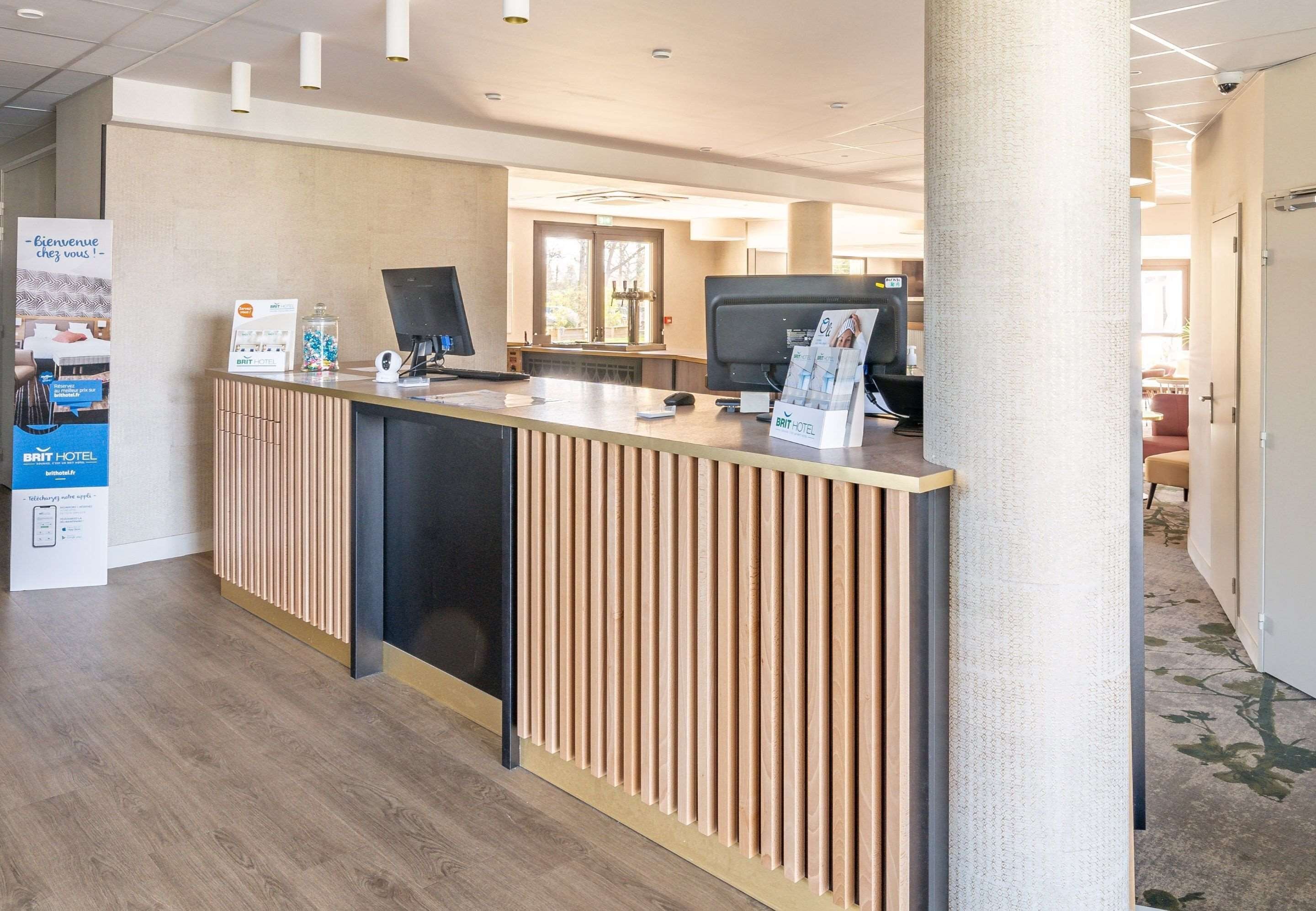 A reception desk with a modern design, a computer, and a sign for BRIT HOTEL.