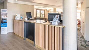 A reception desk with a modern design, a computer, and a sign for BRIT HOTEL.