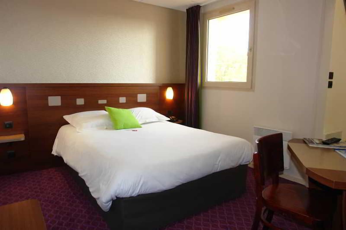 Habitación de hotel con una cama, un escritorio y una silla.