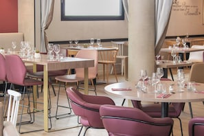 A restaurant with round tables and chairs, some with pink cushions.