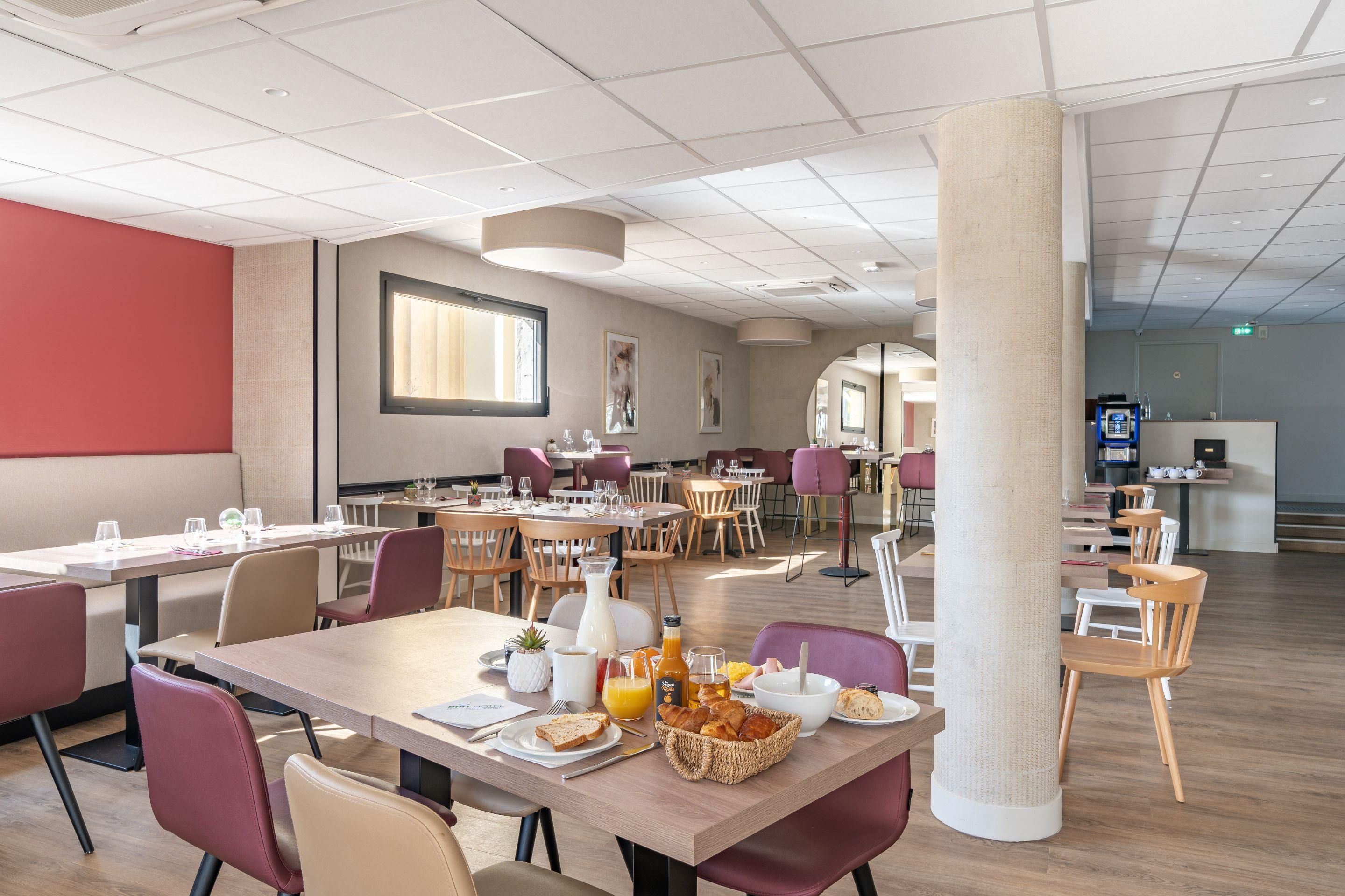 A modern dining area with multiple tables and chairs, a large pillar, and a view of the adjacent room.