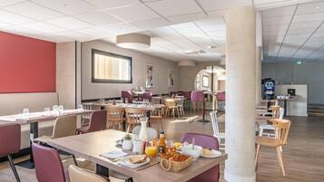 A modern dining area with multiple tables and chairs, a large pillar, and a view of the adjacent room.