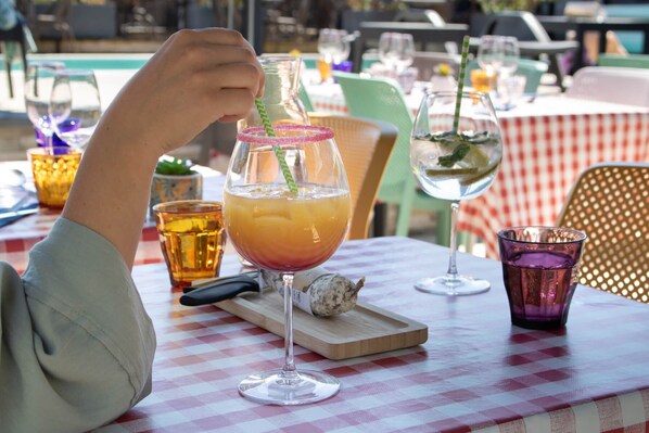 A table with a checkered tablecloth, a glass with a straw, and a bottle with a label.