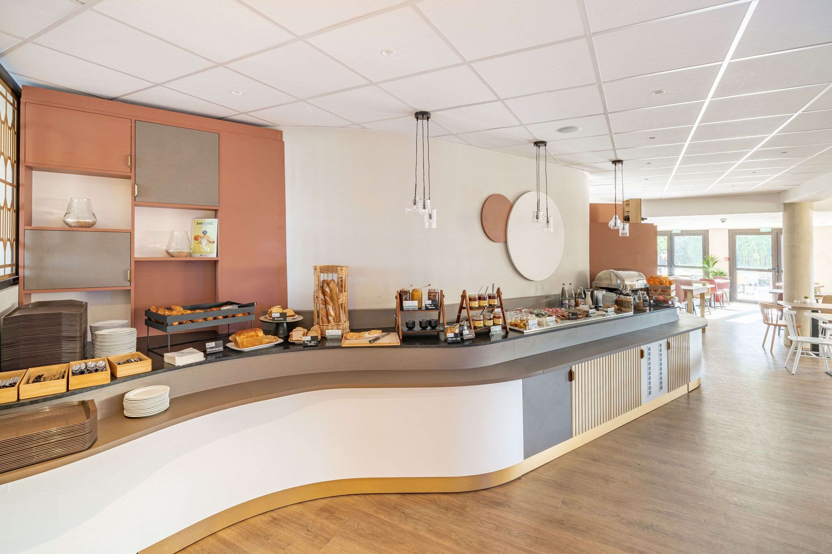 En modern frukostbar med en böjd design, som erbjuder ett varierat utbud av frukosträtter och en kaffestation.