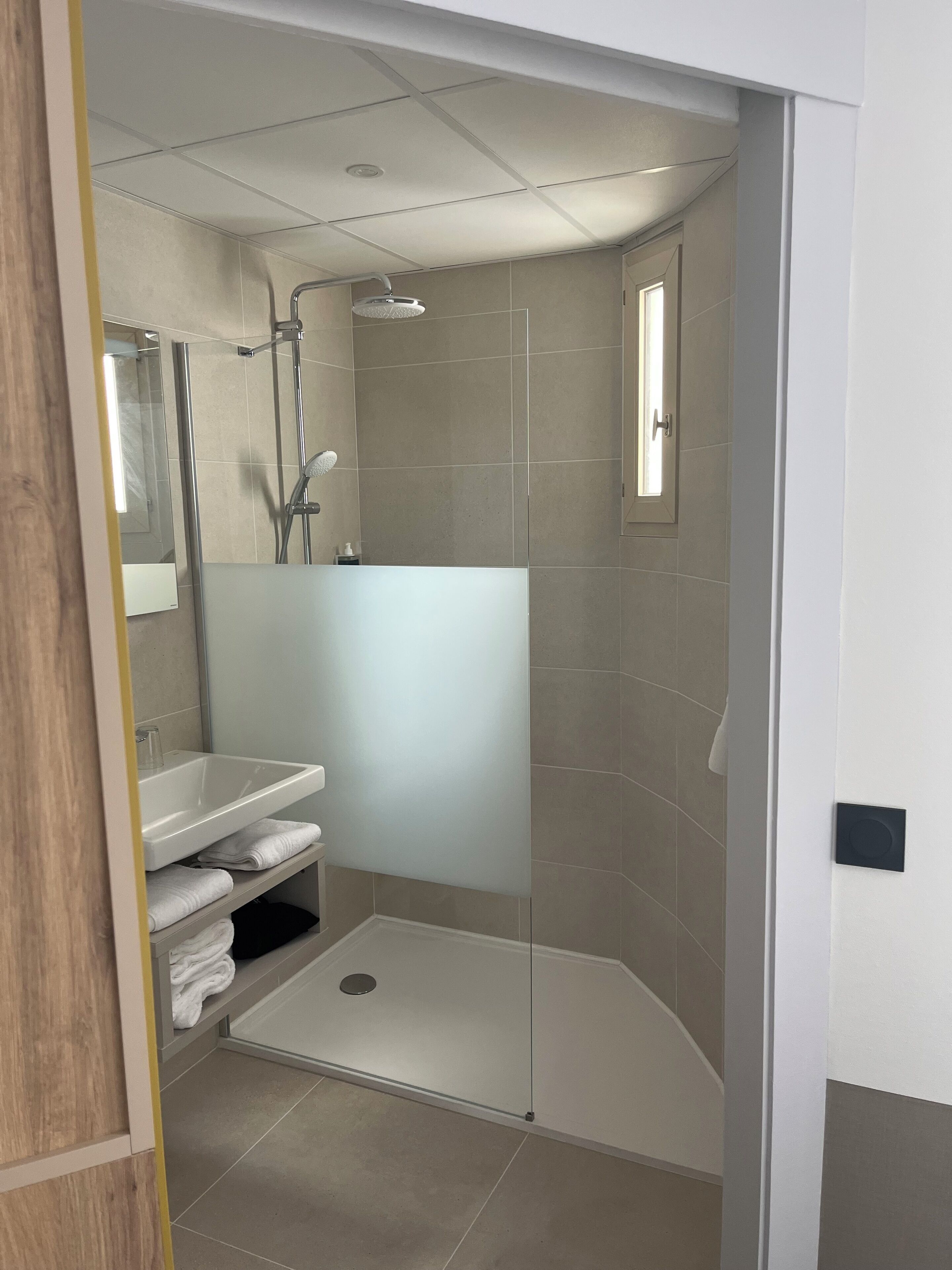 A modern bathroom with a shower, sink, and toilet.