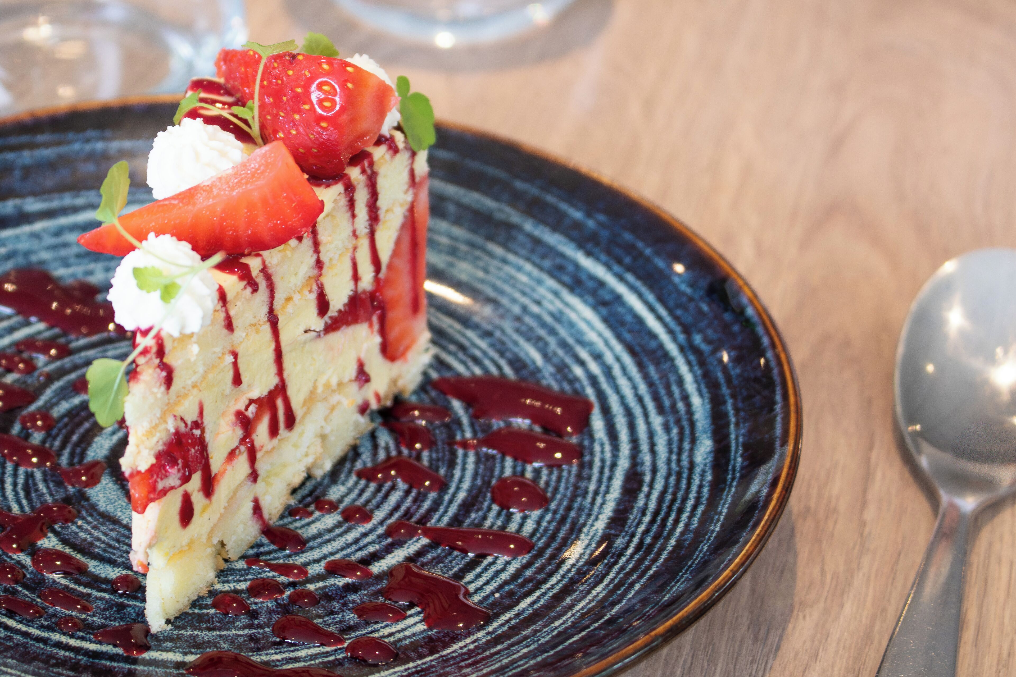 Una porción de pastel con fresas y crema en un plato.