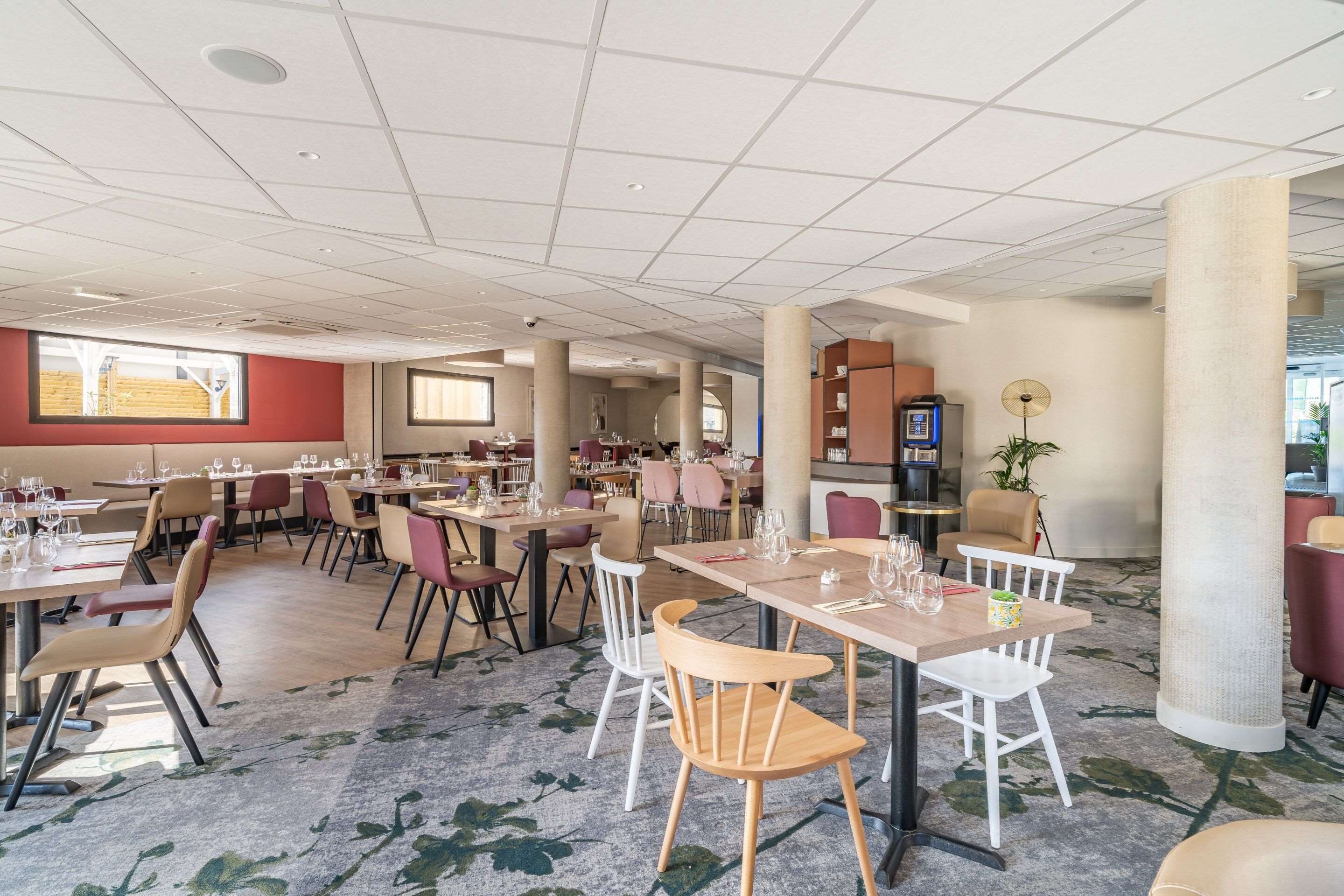 Un vaste espace dédié à la salle à manger, avec de nombreuses tables et chaises, de grandes fenêtres et un design moderne au niveau du plafond.