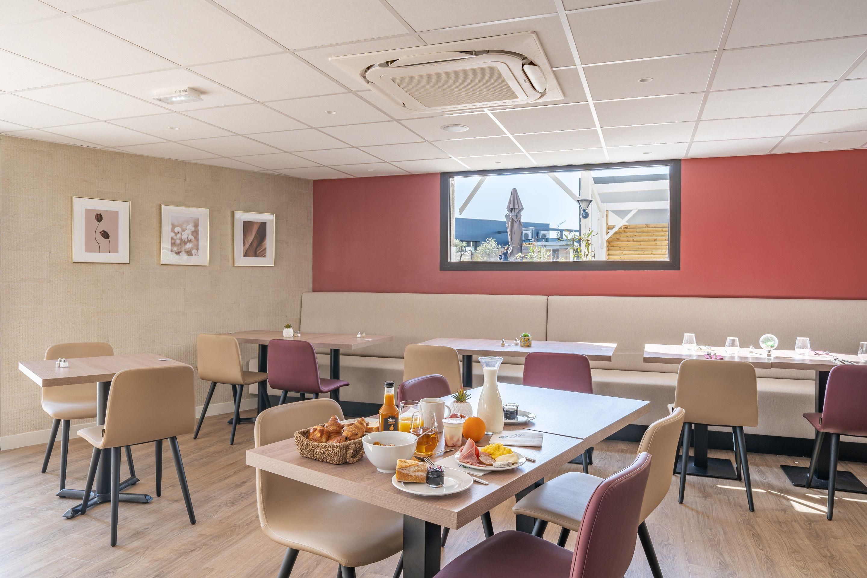 Un comedor moderno con varias mesas y sillas, un ventanal con vistas y un techo con iluminación empotrada.