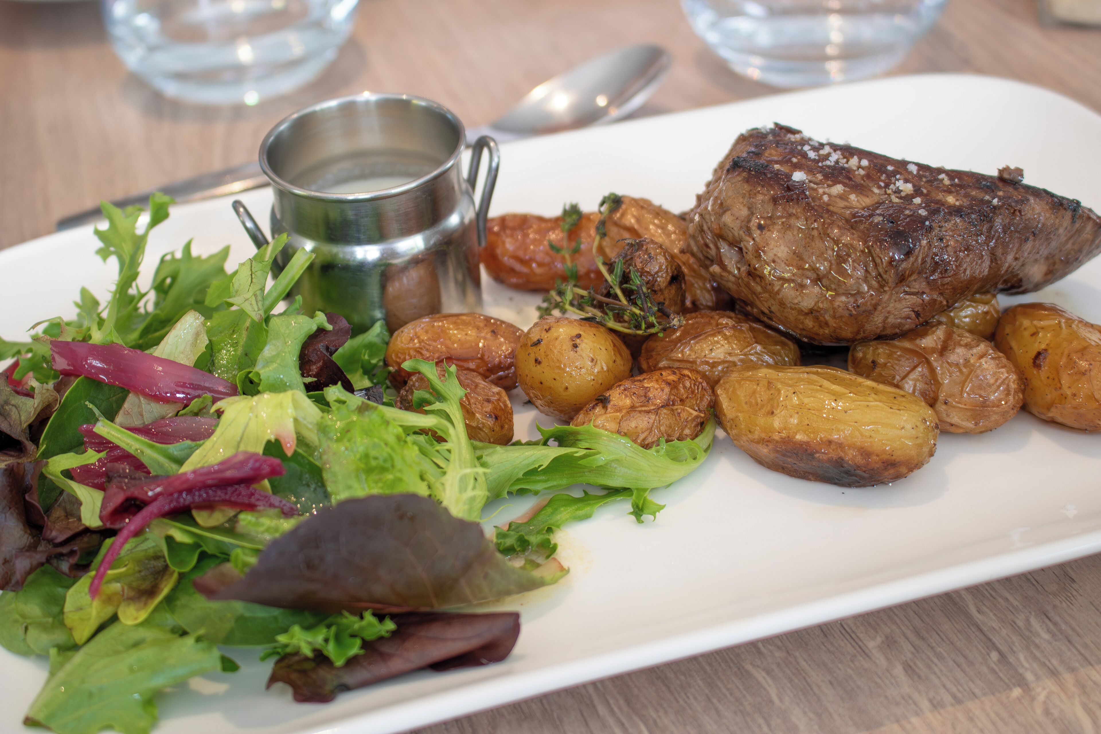 A plate with roasted meat, potatoes, and a salad.