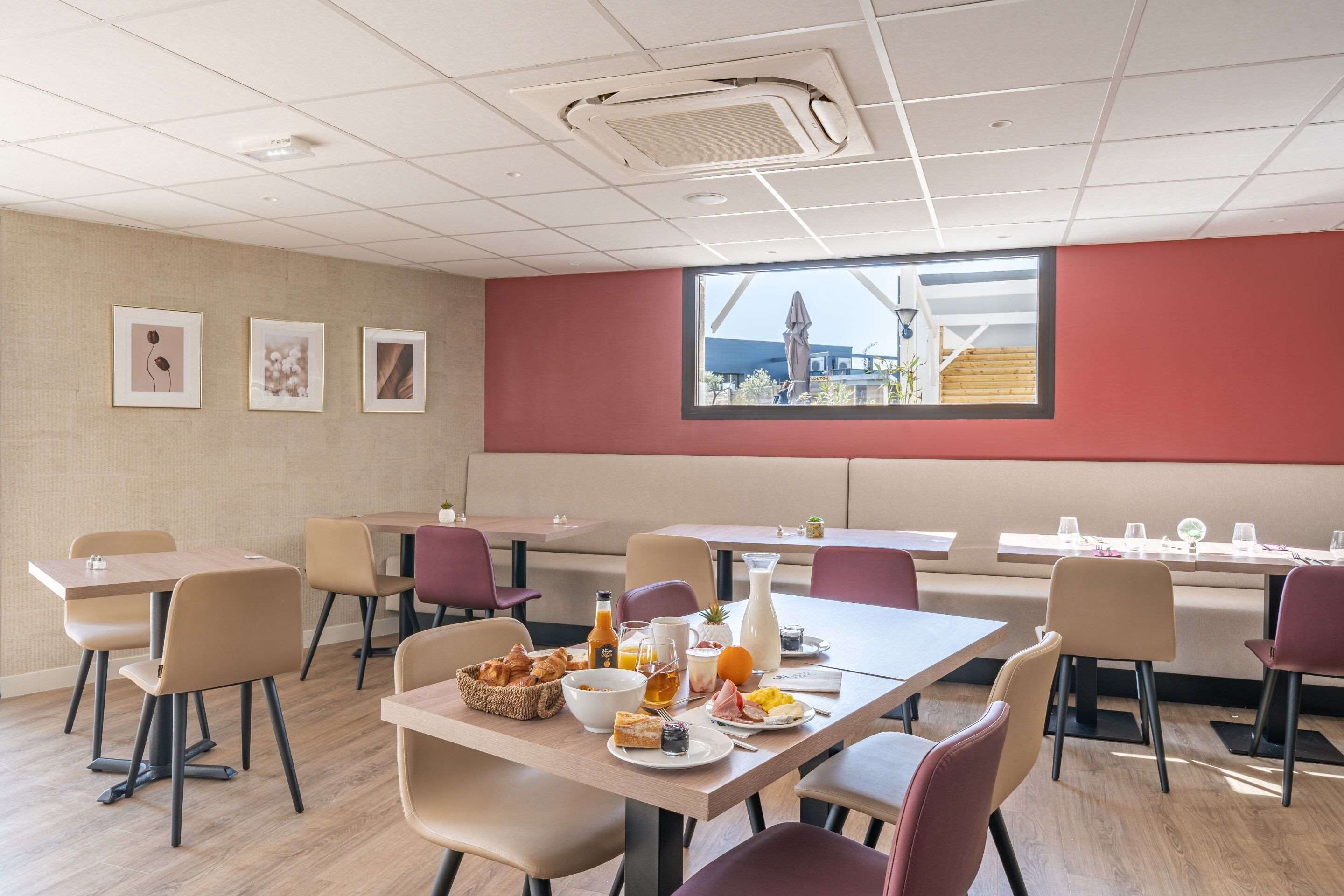 A dining area with tables and chairs, breakfast items, and framed pictures on the wall.