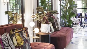 A modern living room with a red sofa, large windows, and potted plants. - Hotel Bienvenue (Paris)
