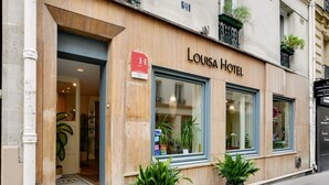 En hotelindgang med facade i træ, store vinduer og plantekasser.