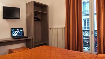 A hotel room with a bed, a wardrobe, a television, and a laptop.