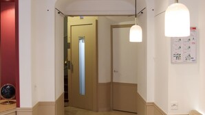 A hotel corridor with a marble floor, a round table, a sofa, and a door leading to another room. - Hotel Little (Paris)