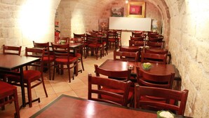 A restaurant with stone walls and wooden tables and chairs. - Hotel Little (Paris)