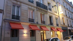 A hotel facade with multiple windows, red awnings, and a sign indicating it is a hotel. - Hotel Little (Paris)