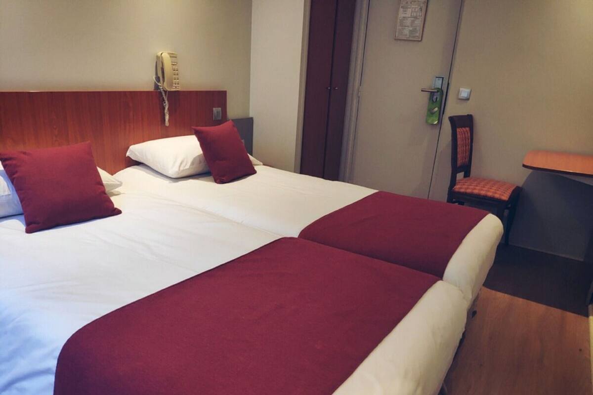 A double bed with two red pillows and a white bedspread.