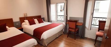 A hotel room with two beds, a small table, and a chair.