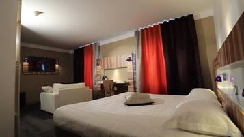 A hotel room with a bed, a desk, a chair, and a television.