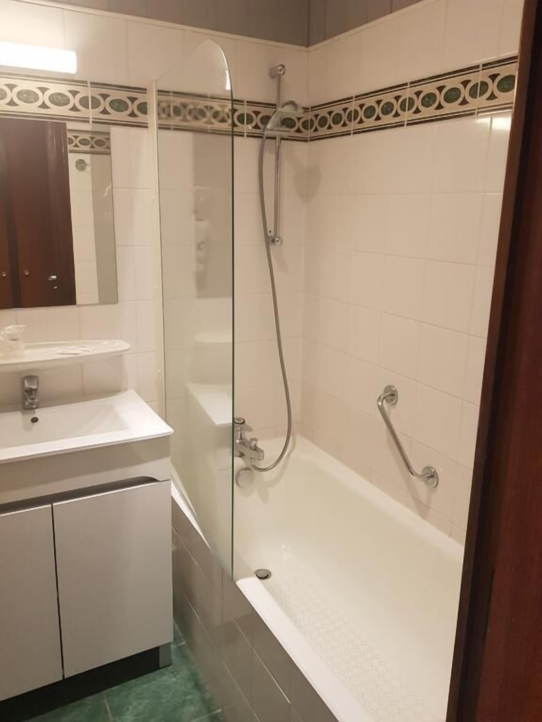 Un baño con ducha envuelta en vidrio, un lavamanos blanco y una bañera.