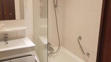 Un baño con ducha envuelta en vidrio, un lavamanos blanco y una bañera.