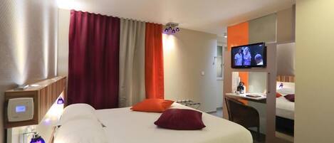 Una habitación de hotel con una cama, un escritorio y una televisión.