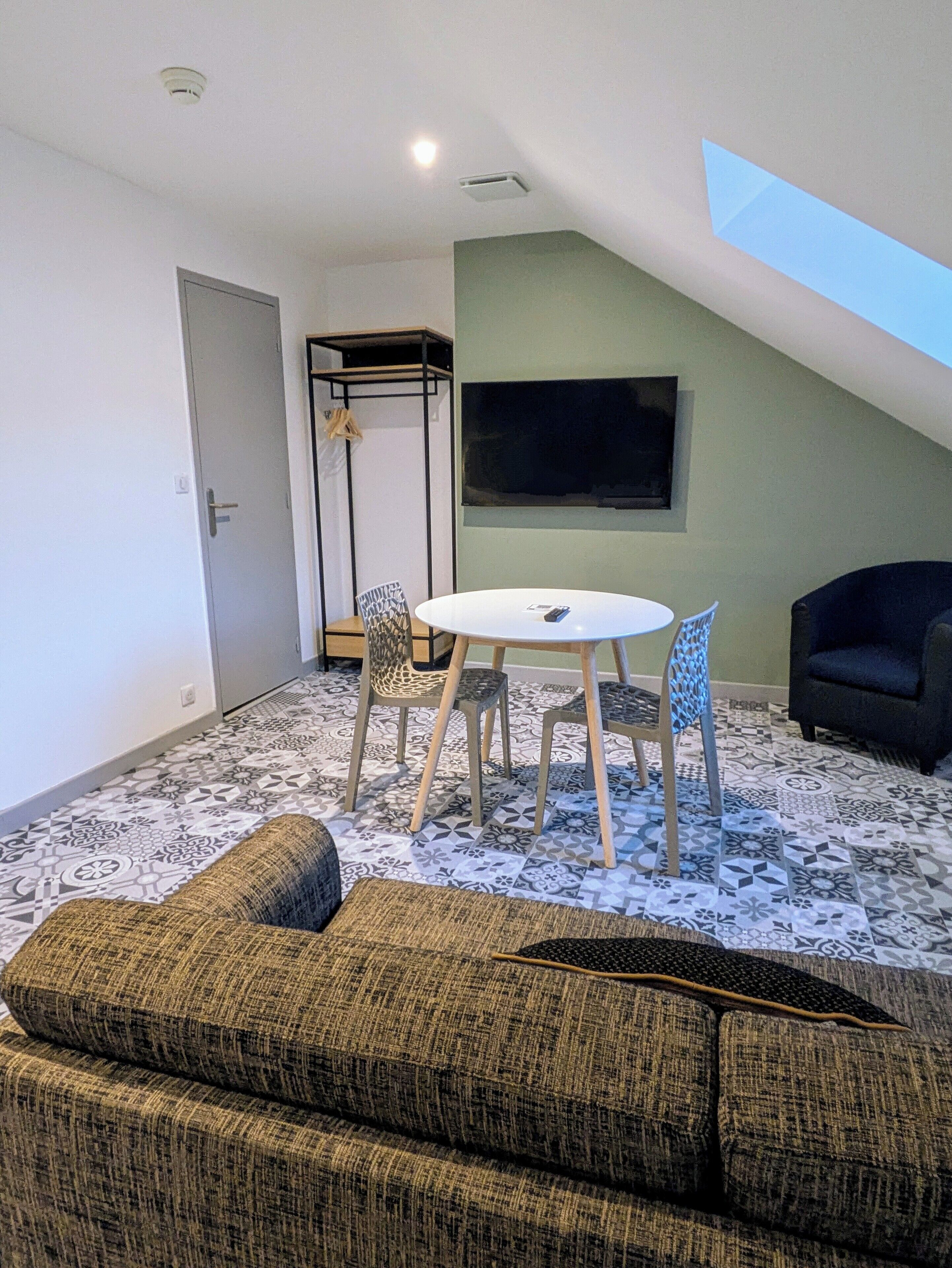 A living room with a high ceiling, a TV mounted on the wall, a dining table with chairs, and a sofa.