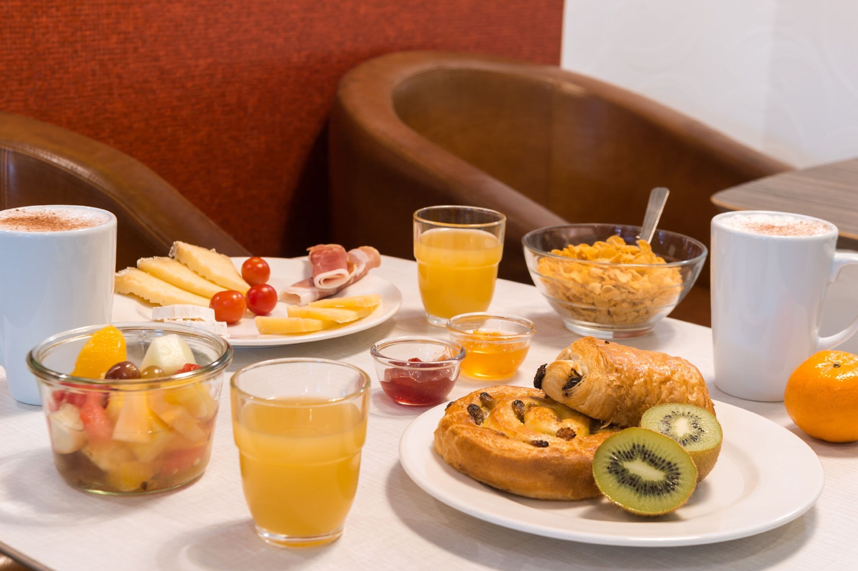 A breakfast setting with various food items and drinks on a table.