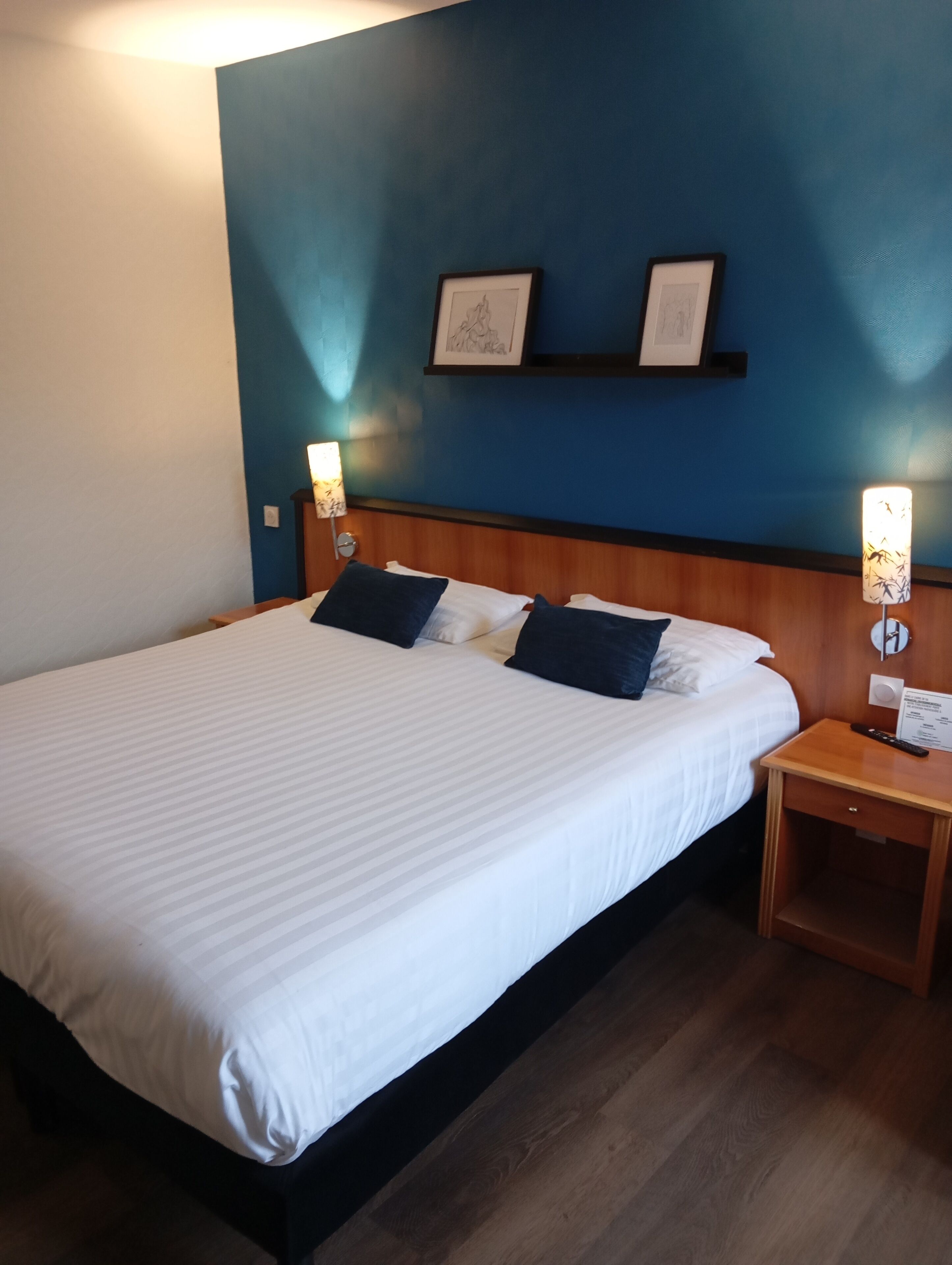 A hotel room with a large bed, two bedside tables, and a blue accent wall.