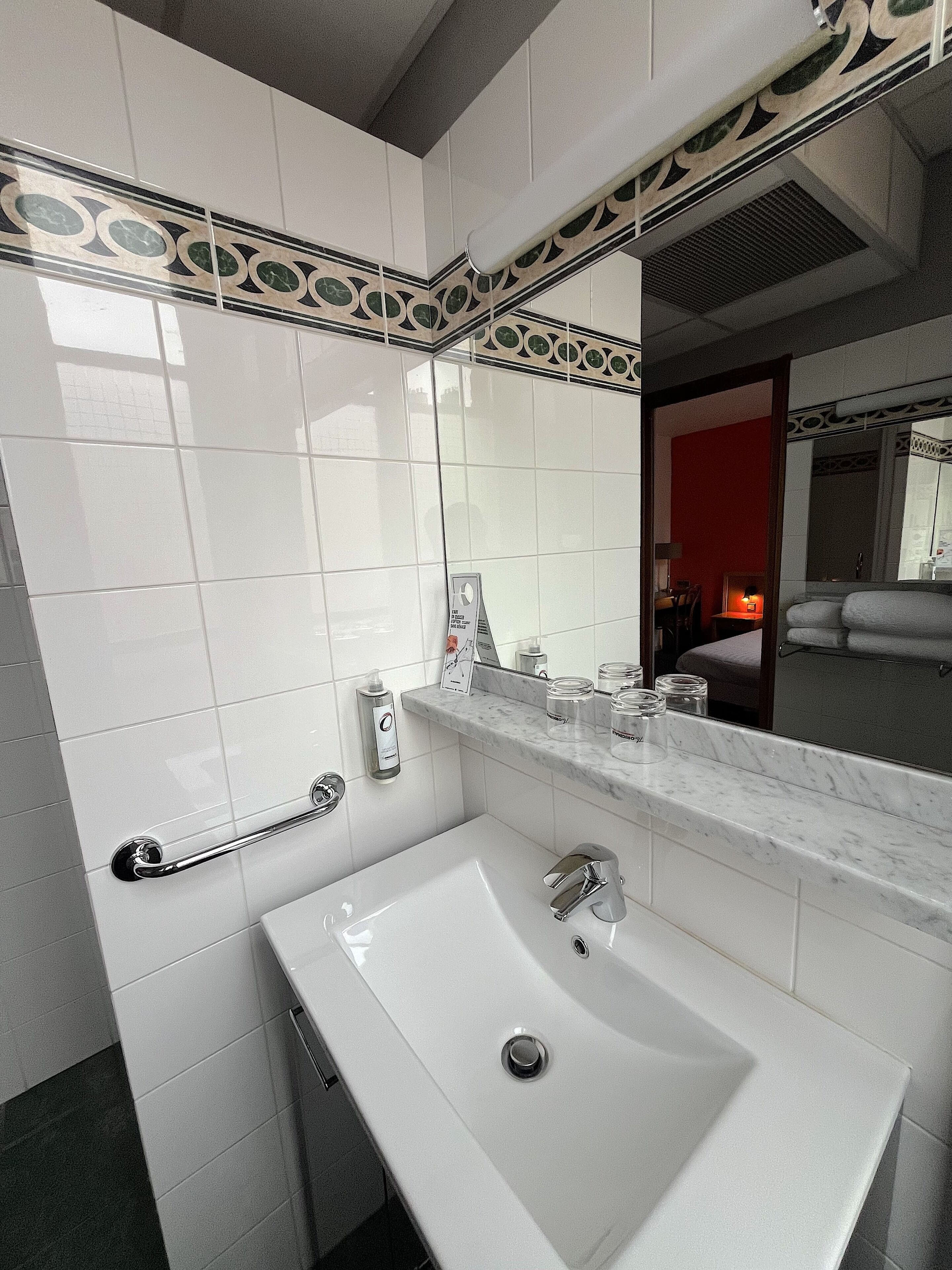 A bathroom with a white sink, a mirror, and a towel rack.