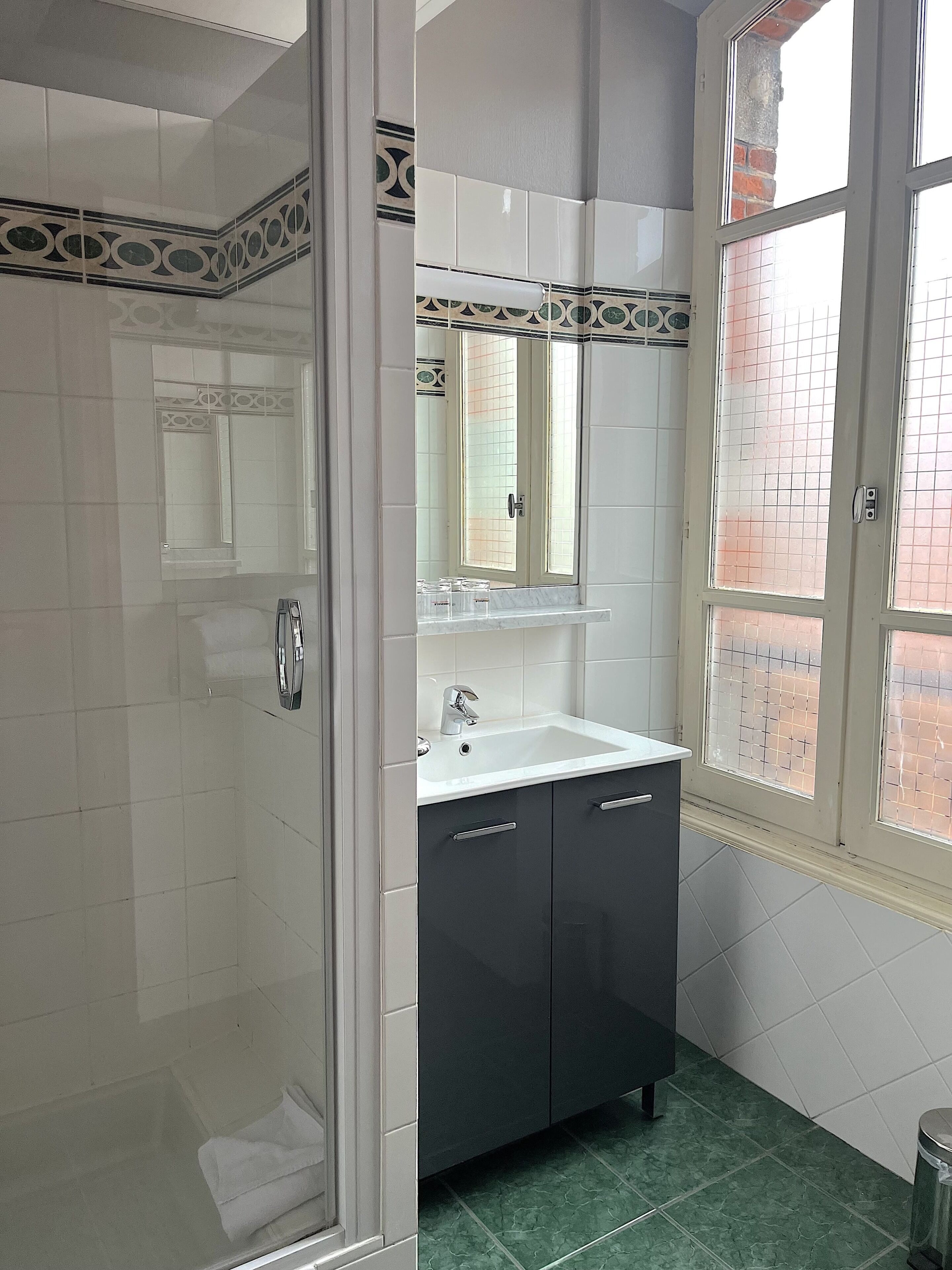 Un baño con ducha, lavamanos y ventana.