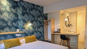 Une chambre d’hôtel comprenant un lit, un bureau avec un miroir et un espace douche.