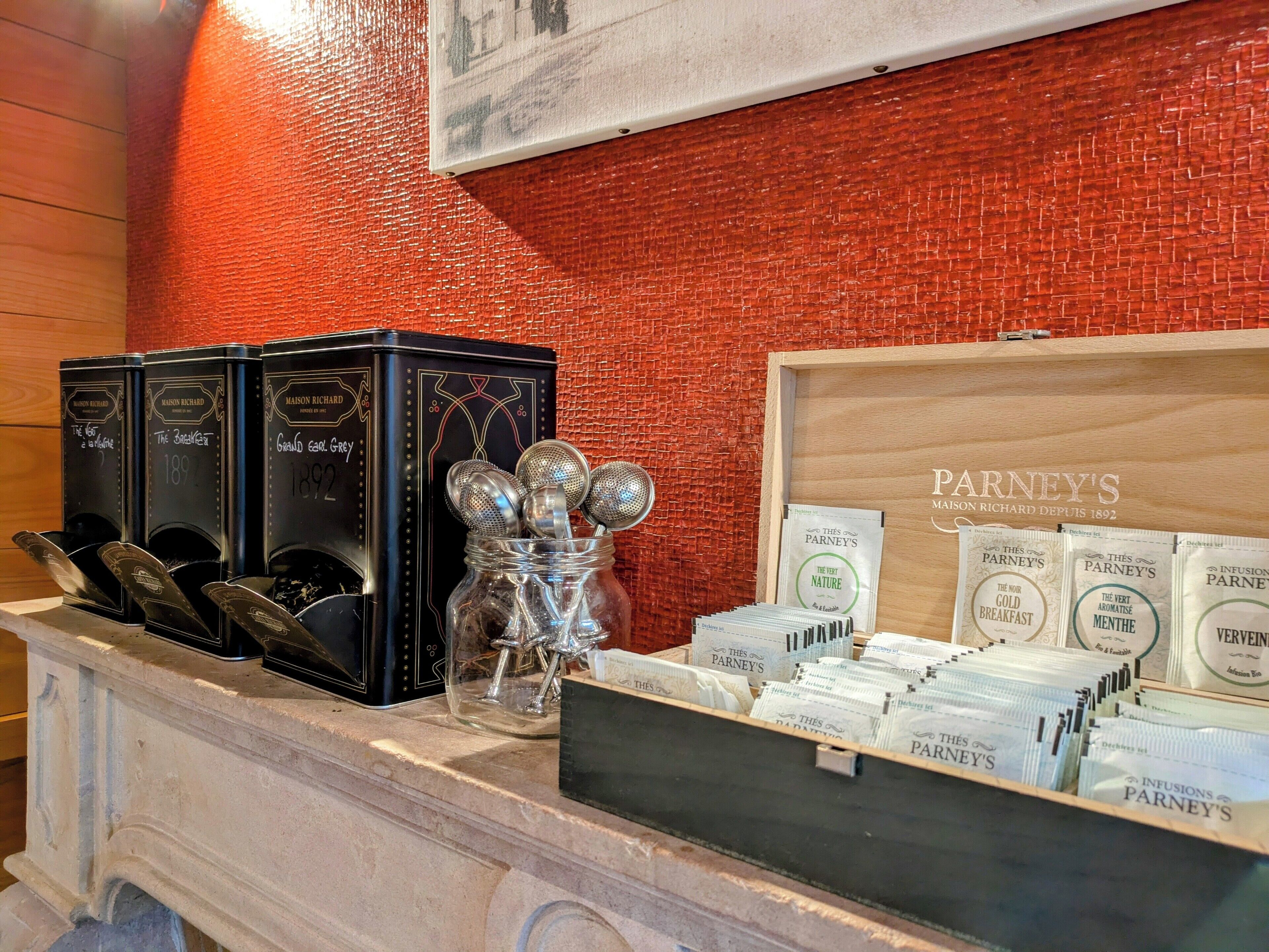 A display of Parney's coffee products, including tins and sachets, on a marble counter with a red brick wall background.