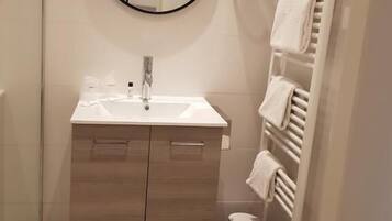 Un baño con tocador de madera, un espejo redondo, un inodoro y un perchero para toallas.