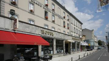 A historic hotel with a red awning, outdoor seating, and a sign for a brasserie.