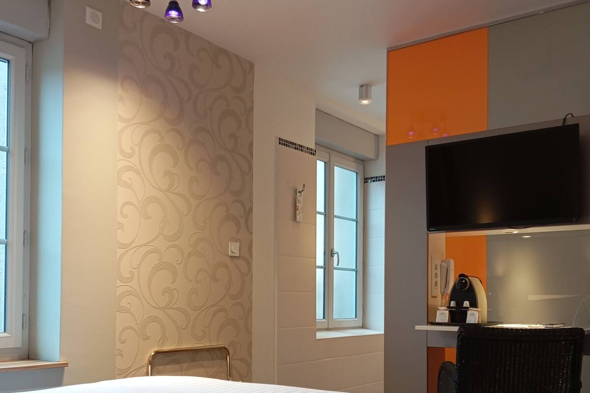 Ein Hotelzimmer mit einem großen Bett, einem Sessel, einem Schreibtisch mit Flachbildfernseher und einem Fenster.