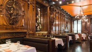 Un restaurant doté de boiseries décoratives, de nappes blanches et de banquettes en cuir.