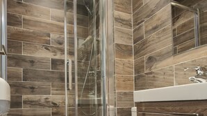 A modern bathroom with a glass shower enclosure, a white toilet, and a wooden vanity. - Hotel Modern'Est (Paris)