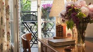 Une pièce avec un bureau en bois, un vase de fleurs, une lampe et une vue sur le balcon extérieur.
