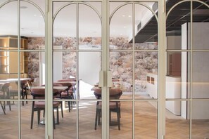 Un espace repas moderne avec des tables et des chaises, un coin cuisine avec un comptoir, et un escalier menant à un niveau supérieur.