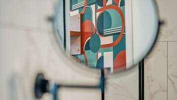 A toilet with a mirror reflecting a bathroom with a tiled floor and a wall-mounted toilet paper holder.
